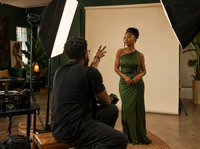 A photographer directing a model in a green dress in a studio